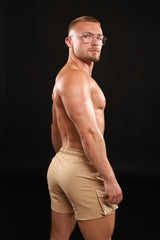 Man wearing beige shorts against a black background