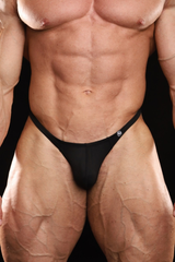 Close-up of a muscular male model wearing a black men's thong-style brief against a black background.